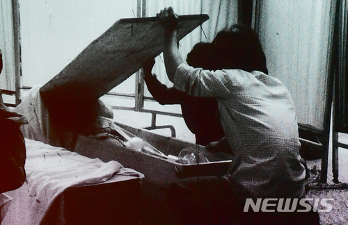 【광주=뉴시스】류형근 기자 = 1980년 5·18민주화운동 당시 계엄군의 잔혹함과 시민들의 분노, 항쟁이 끝난 뒤 광주 모습이 담긴 영상이 38년만인 9일 오후 광주 동구 국립아시아문화전당 극장3에서 처음 공개됐다. 한 가족이 관속에 잠들어 있는 희생자를 확인하고 있다. 2018.05.09. (사진=5·18민주화운동기록관 공개 영상 촬영) photo@newsis.com