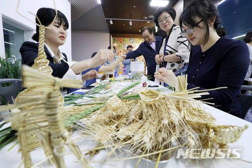 [서울=뉴시스]전신 기자 = 14일 서울시청 시민청에서 농촌진흥청 국립식량과학원 주최로 열린 우리밀 특별전시회를 찾은 시민들이 밀짚공예 체험을 하고 있다. 2018.05.14. photo1006@newsis.com