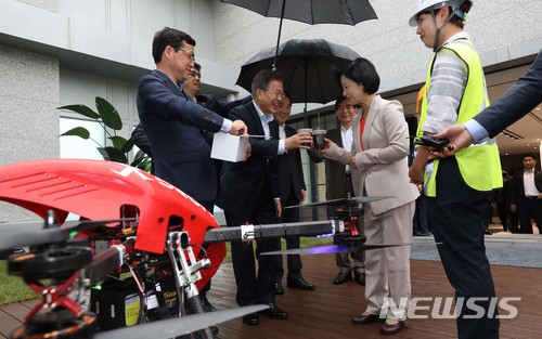 【서울=뉴시스】전신 기자 = 문재인 대통령이 17일 서울 마곡 R&D 단지에서 열린 혁신성장 점검회의에 앞서 사전환담 중 드론이 운반한 커피음료를 받고 추미애 더불어민주당 대표와 대화하고 있다. 2018.05.17.&nbsp;&nbsp; photo1006@newsis.com