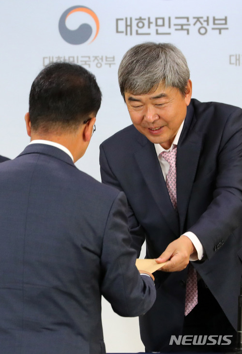 【서울=뉴시스】배훈식 기자 = 23일 오후 서울 종로구 정부서울청사 브리핑실에서 유창조(오른쪽) 면세점 제도 개선 TF 위원장이 기획재정부 담당자에게 면세점 제도 개선 권고안을 전달하고 있다. 2018.05.23. dahora83@newsis.com