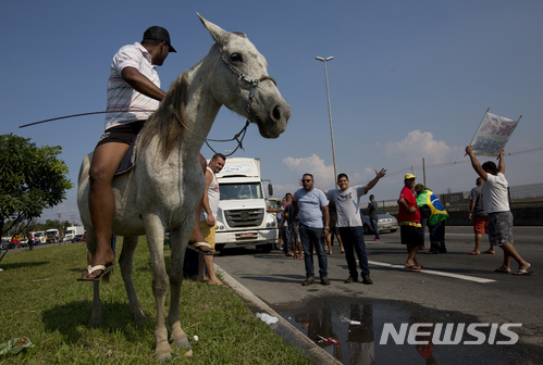 【두케 데 카샤스( 브라질) = AP/뉴시스】 브라질의 트럭운송업계가 유가 인상에 반발 총파업에 들어가면서 트럭운전사들이 고속도로를 막고 말을 타고 있다.&nbsp; 파업이 8일째 계속된 28일 현재 전국의 학교 수천 곳이 문을 닫았고 주유소마다 긴 줄이 늘어섰으며 많은 항공편이 취소되었다.&nbsp;&nbsp;&nbsp;&nbsp; 