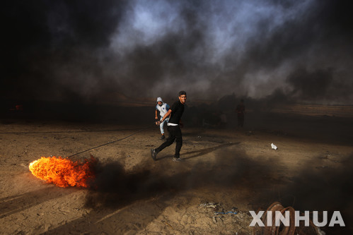 【칸 유니스( 가자지구) = 신화/뉴시스】 5월 25일 팔레스타인 시위대가 가자지구 이스라엘과의 국경지대에 있는 칸 유니스 부근에서 타이어에 불을 붙여 이스라엘군과 대치하고 있다. 이스라엘 군은 이에 대한 보복으로 다음 날인 26일 밤 칸유니스 등 두 곳에 대해 대규모 폭격을 감행했다.&nbsp;&nbsp; 