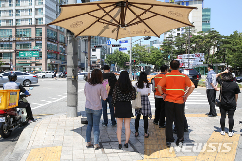 【서울=뉴시스】 한여름 날씨를 보인 1일 서울 성동구 왕십리 오거리 횡단보도에 설치된 무더위 그늘막 아래서 주민들이 뜨거운 햇볕을 피하고 있다. 2018.06.01. (사진=성동구 제공) photo@newsis.com