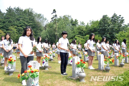 【익산=뉴시스】강명수 기자 = 지난해 제63회 현충일 전북 익산시 팔동군경묘지에서 순국선열과 호국영령을 추모하는 추념식이 열렸다. 사진은 익산지역 학생들이 146명이 잠든 묘역에 헌화하는 모습. 2018.06.06. smister@newsis.com
