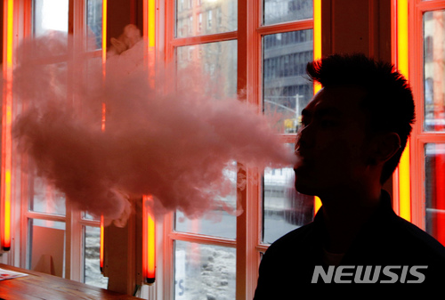 FILE - In this Feb. 20, 2014 file photo, a customer exhales vapor from an e-cigarette at a store in New York. A growing number of e-cigarette and vaporizer sellers have started offering college scholarships as a way to get their brands listed on university websites and to get students to write essays about the potential benefits of vaping. (AP Photo/Frank Franklin II, File)