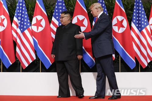 【싱가포르=AP/뉴시스】도널드 트럼프 미국 대통령이 12일 싱가포르 카펠라 호텔에서 김정은 북한 국무위원장과 만나 악수한 후 길을 안내하는 듯한 동작을 취하고 있다. 2018.06.12