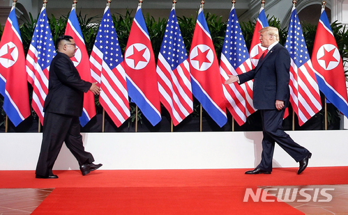 【서울=뉴시스】 북미 정상회담이 열린 12일 오전 싱가포르 센토사섬 카펠라 호텔 회담장에서 북한 김정은(왼쪽) 위원장과 미국 도널드 트럼프 대통령이 역사적인 회담에 앞서 세기의 악수를 하기 위해 걸어오며 손을 내밀고 있다. 2018.06.12. (사진=싱가포르 통신정보부 제공) photo@newsis.com
