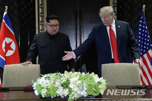 [싱가포르=AP/뉴시스]도널드 트럼프 미 대통령(오른쪽)이 12일 싱가포르 센토사섬의 카펠라 호텔에서 열린 김정은 북한 국무위원장과의 사상 첫 북미 정상회담 후 합의문에 서명하기에 앞서 김 위원장에게 자리에 앉으라고 권하고 있다. 2018.6.12