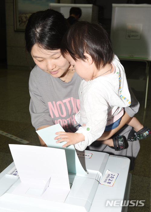 【울산=뉴시스】배병수 기자 = 제7회 전국동시지방선거일인 13일 오전 울산시 남구 삼산동 제5투표소에서 한 여성이 자녀와 함께 투표용지를 투표함에 넣고 있다. 2018.06.13.  bbs@newsis.com.