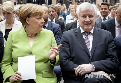 【베를린=AP/뉴시스】 앙겔라 메르켈 독일 총리가 20일 호르스트 제호퍼 내무장관과 추모식장에 나란히 앉아 있아 이야기를 나누고 있다. 메르켈 총리는 이주자의 망명지위 신청 문제로 보수파 동맹인 기사련 대표인 제호퍼 장관과 갈등을 빚고 있다. 2018. 6. 20.