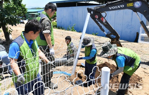 【충주=뉴시스】강신욱 기자 = 22일 충북 충주시 중앙탑면에서 공군 19전투비행단 나래봉사단이 담장 유실로 불편을 겪는 가정에 철제 울타리를 설치하고 있다. 2018.06.22. (사진=공군 19전투비행단 제공) photo@newsis.com