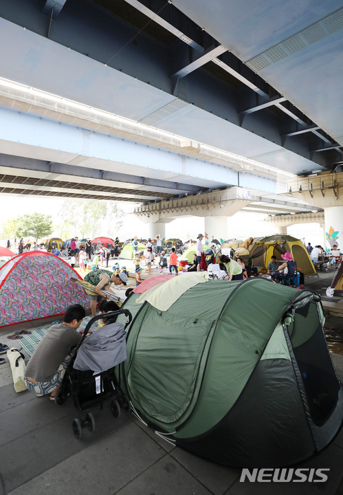 【서울=뉴시스】이영환 기자 = 연일 불볕더위가 이어지며 서울에 올해 첫 폭염주의보가 내린 24일 오후 서울 영등포구 여의도 마포대교 밑에서 시민들이 텐트를 치고 휴식을 취하고 있다. 2018.06.24. 20hwan@newsis.com