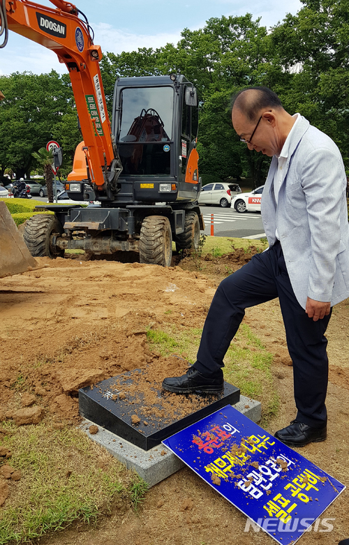 【창원=뉴시스】 홍정명 기자 = 27일 오후 홍준표 전 경남지사가 2016년 6월 1일 도청 정문 가운데에 심은 '채무제로 기념 나무‘가 철거된 후 적폐청산과민주사회건설경남운동본부 김영만 상임대표가 표지석도 철거해야 한다면서 표지석을 발로 밟고 있다.2018.06.27. hjm@newsis.com