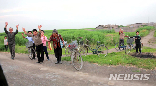 【서울=뉴시스】김정은 북한 국무위원장이 신도군 갈대 종합농장을 시찰했다고 조선중앙TV가 30일 보도했다. 사진은 북한 신도군 주민들이 김정은 위원장을 향해 손을 흔드는 모습이다. 2018.06.30. (사진=조선중앙TV 캡처) photo@newsis.com