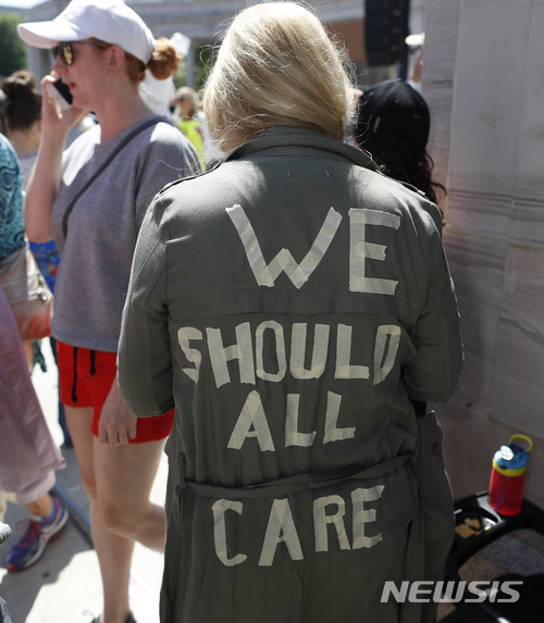 【러브랜드=AP/뉴시스】30일(현지시간) 도널드 트럼프 미국 대통령의 무관용 이민정책 비판 시위에서 한 여성이 '우리 모두 상관해야 한다'고 적힌 재킷을 입고 있다. 트럼프 대통령의 부인 멜라니아 여사가 밀입국 아동수용소 방문 당시 '나는 정말 상관 안 한다, 당신은?'(I REALLY DON’T CARE, DO U?)라는 문구가 적힌 재킷을 입어 논란을 일으킨 것을 풍자했다. 2018.7.1. 