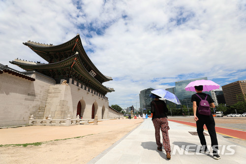 【서울=뉴시스】김선웅 기자 = 제7호 태풍 '쁘라삐룬'의 경로가 예상보다 동쪽으로 치우치면서 수도권 지역이 태풍 영향권에서 벗어났으나 태풍 수증기 영향으로 서울 최고 기온이 32도를 기록했다고 기상청이 관측한 가운데 3일 오후 서울 종로구 경복궁 인근에서 시민들이 양산을 쓰고 걷는 너머로 맑고 뭉게구름 가득한 하늘이 보인다. 2018.07.03. mangusta@newsis.com