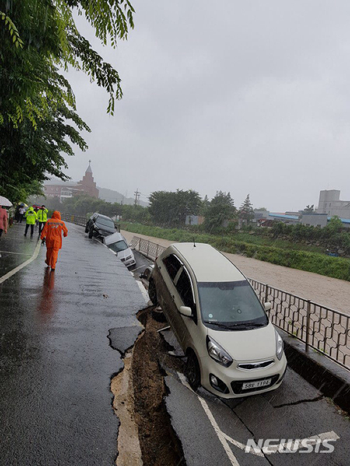 【양산=뉴시스】안지율 기자 = 7호 태풍 ‘쁘라삐룬’이 북상 중인 3일 오후 4시12분께 경남 양산시 덕계동 한 아파트 옆 도로변에 설치된 높이 4m, 길이 20여m의 주차장이 침하되는 사고가 발생했다. 이 사고로 주차된 승용차 4대가 내려않았으나 다행히 탑승자가 없어 인명피해는 발생하지 않았다. 2018.07.03. (사진=경남도 소방본부 제공) photo@newsis.com