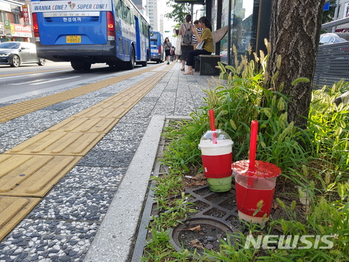 【서울=뉴시스】김가윤 기자 = 서울 서대문구 이대역 근처 버스정류장. 가로수 옆에 음료가 담긴 얼음컵 2개가 놓여 있다. 2018.07.04.  yoon@newsis.com