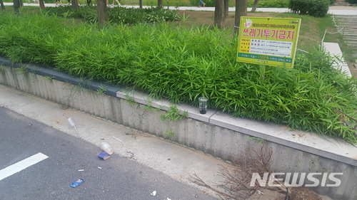 【서울=뉴시스】 임얼 기자 = 쓰레기 무단투기 단속 팻말 아래 공원 주변에서 발생한 쓰레기가 버려져 있다. 2018.07.03. limeol@newsis.com
