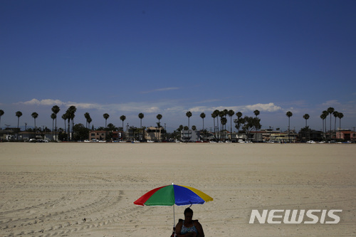 【롱비치(미 캘리포니아주)=AP/뉴시스】지난 6일 미 캘리포니아주 롱비치의 해변에 한 남성이 비치 파라솔 아래 앉아 있다. 미 국립기상국은 23일(현지시간) 미국 남서부 지역의 기온이 25일까지 49도(화씨 120도)에 이를 것이라며 폭염경보를 발령했다. 2018.7.24
