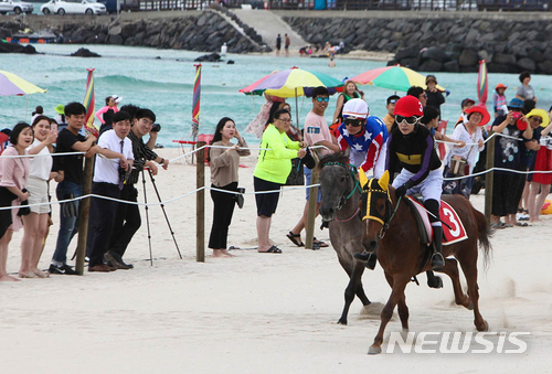 【제주=뉴시스】우장호 기자 = 8일 오후 제주시 애월읍 곽지해수욕장에서 렛츠런파크 제주 주최로 이색 볼거리인 '제주마 해변경주'가 펼쳐지고 있다. 이날 해수욕장에는 제주마 혈통 8마리의 경주마가 백사장 250m를 달리며 치열한 경쟁을 했다. 2018.07.08. (사진=렛츠런파크 제주 제공) woo1223@newsis.com