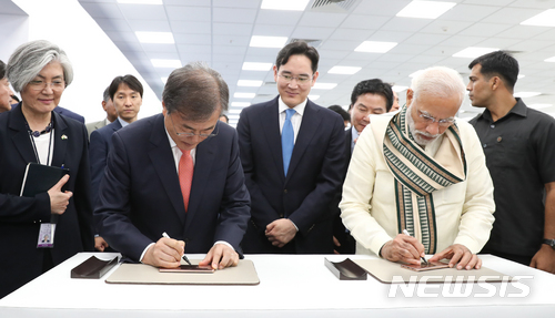 【뉴델리(인도)=뉴시스】박진희 기자 = 문재인 대통령은 9일(현지시간) 나렌드라 모디 (Narendra Modi) 인도 총리와 함께 인도 뉴델리 인근 노이다 공단에서 개최된 ‘삼성전자 제2공장 준공식’에 참석하여 신규라인에서 생산된 휴대폰에 서명을 하고 있다. 2018.07.09. pak7130@newsis.com