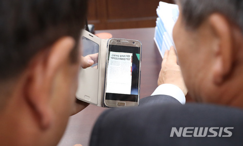 【세종=뉴시스】강종민 기자 = 10일 오후 정부세종청사에서 열린 최저임금위원회 전원회의에서 이동응 사용자위원과 이성경 근로자위원이 신문기사를 함께 보고 있다. 2018.07.10. ppkjm@newsis.com