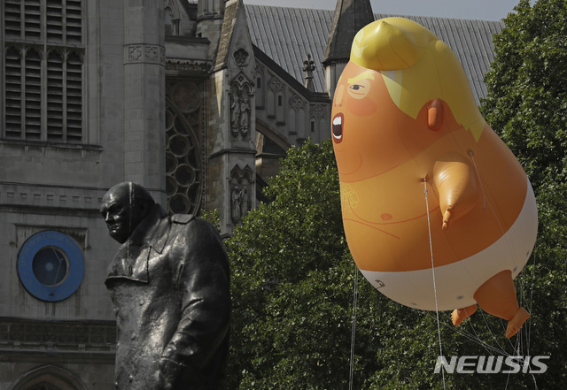 【런던=AP/뉴시스】 트럼프 미 대통령의 영국 방문을 반대하는 시위대가 13일 오전 런던 웨스트민스터 의회 광장에서 트럼프를 '기저귀 차고 한 손에 트위터 휴대폰을 들고 소리 지르는 베이비'로 묘사한 카툰 고무인형을 하늘로 올려 보내고 있다. 팽창하면 6m 크기에 달하는 인형이 처칠 전 수상의 동상을 지나 솟아오르는 중이다. 이 시간 트럼프는 숙소인 주영국 미국 대사 관저에서 샌드허스트 군사관학교에 가 잠시 머문 뒤 런던과 작별하고&nbsp; 외곽 지역 행사장으로 갔다. 2018. 7. 13. 