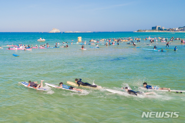 【고성(강원)=뉴시스】김경목 기자 = 해수욕장 개장 후 첫 주말을 맞은 강원 고성군 삼포해수욕장에서 지난 14일 열린 서핑과 음악이 함께하는 2018 삼포해변 서핑축제에 참여한 서퍼들이 서핑을 들고 바다로 뛰어들고 있다. 2018.07.15. (사진=고성군청 제공) photo@newsis.com