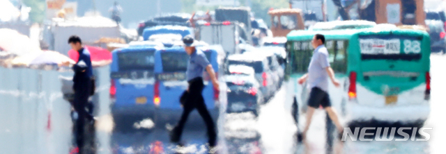 【서울=뉴시스】박주성 기자 = 서울에 올해 첫 폭염경보가 발효된 가운데 16일 오후 아지랑이가 피어오르는 서울 여의도 아스팔트 위를 시민들이 걷고 있다. 2018.07.16.&nbsp; park7691@newsis.com