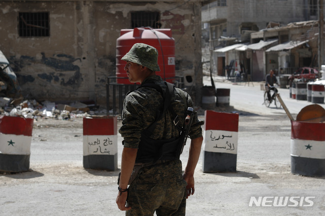 【동구타( 시리아) = AP/뉴시스】 15일 시리아 정부군 한 명이 다마스쿠스 부근 동구타 지역의 검문소에서 행인들을 감시하고 있다. 차량통제용 드럼통에는 아랍어로 "아사드의 시리아" "아랍 바샤르의 왕관"이라고 쓰여있다. 2017.07.27&nbsp;&nbsp;&nbsp; 