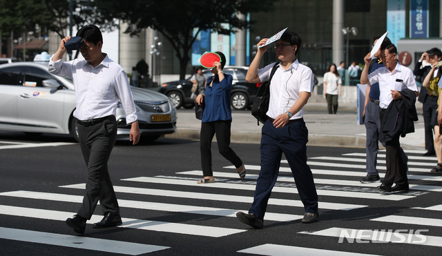 【서울=뉴시스】김진아 기자 = 찜통더위가 이어진 18일 오전 서울 종로구 광화문 네거리에서 시민들이 내리쬐는 햇볕을 가리며 출근하고 있다. 2018.07.18.&nbsp; bluesoda@newsis.com
