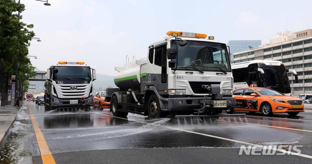 【서울=뉴시스】고범준 기자 = 18일 오후 서울 종로구 세종대로 세종문화회관 앞 도로에서 종로구 물청소 차량들이 하절기 특별 도로 물청소의 날을 맞아 물청소 작업을 하고 있다. 2018.07.18.&nbsp; bjko@newsis.com