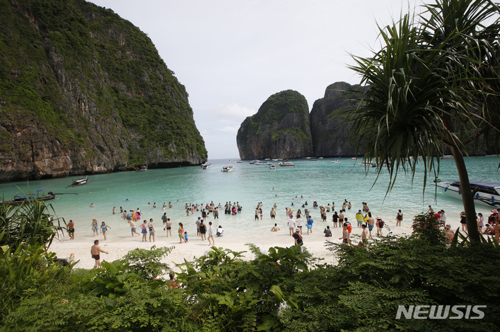 [끄라비(태국)=AP/뉴시스]2018년 5월31일 관광객들이 태국 끄라비 지방의 피피섬 마야 베이 해변을 걷고 있다. 2021.11.16