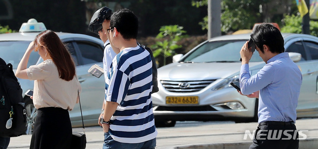 【서울=뉴시스】이영환 기자 = 폭염 경보가 이어지고 있는 20일 오전 서울 종로구 광화문 네거리에서 시민들이 따가운 햇빛을 손으로 가리며 출근길 발걸음을 재촉하고 있다. 2018.07.20. 20hwan@newsis.com