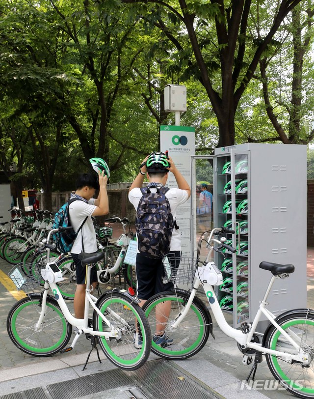 【서울=뉴시스】고범준 기자 = 서울시설공단이 지난 19일 공공자전거 '따릉이'를 이용할 때 안전모 무료 대여 사업을 한 달간 시범 운영한다고 밝혔다. 따릉이 이용자들의 안전모 착용이 의무화되는 9월을 앞두고 여의도 지역 따릉이 대여소 30곳에서 안전모 500개를 시범 대여해 준다. 사진은 20일 오후 서울 영등포구 여의나루역 인근 안전모 보관소 앞에서 시민들이 따릉이와 안전모를 이용하는 모습. 2018.07.20.&nbsp; bjko@newsis.com