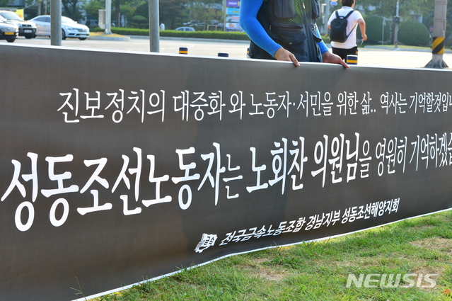 【창원=뉴시스】김기진 기자 = 26일 고(故) 노회찬 정의당 원내대표의 영정이 성동조선 노동자들의 농성 장소인 경남 도청 앞에서 잠시 머무는 가운데 성동조선 노동자들이 펼침막을 들고 있다. 2018.07.26.&nbsp; sky@newsis.com