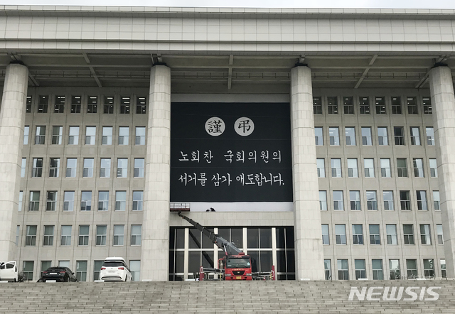 【서울=뉴시스】고승민 기자 = 26일 오전 서울 여의도 국회 본청 앞면 외벽에 관계자들이 정의당 故 노회찬 의원을 추모하는 대형 현수막을 설치하고 있다. 2018.07.26.&nbsp; kkssmm99@newsis.com 