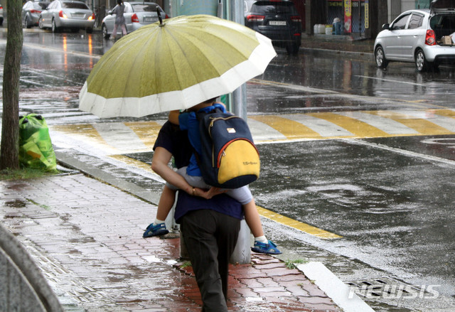 [진주=뉴시스] 지난 2018년 7월 30일 한 할머니가 우산을 쓰고 병설유치원을 마치고 나온 손자를 등에 업고 집으로 향하는 모습.2018.07.30.jkgyu@newsis.com