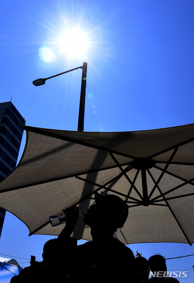 【부산=뉴시스】 하경민 기자 = 부산지역에 폭염특보가 23일째 지속되고, 열대야 현상도 16일째 발생하는 등 밤낮으로 폭염이 기승을 부리고 있는 가운데 2일 오전 부산 해운대해수욕장 입구 횡단보도에 설치된 그늘막에서 한 피서객들이 물을 마시고 있다. 2018.08.02.&nbsp; yulnetphoto@newsis.com