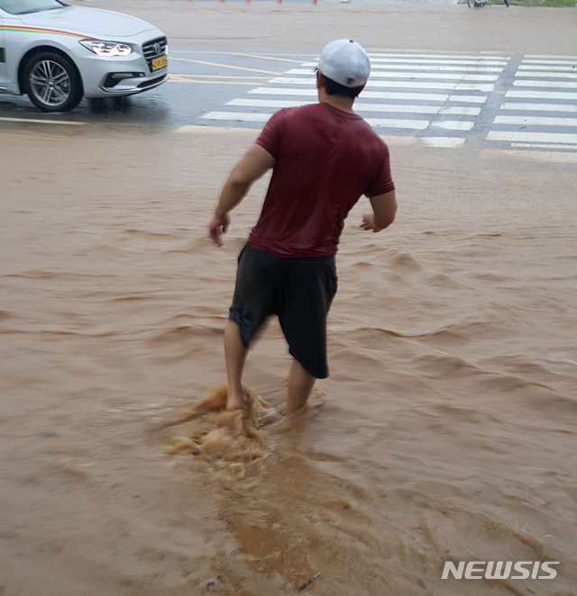 【강릉=뉴시스】김경목 기자 = 6일 오전 호우경보가 발령된 강원 강릉시에 많은 비가 내려 도심 도로 곳곳이 침수된 가운데 한 시민이 맨발로 흙탕물로 가득한 횡단보도를 건너고 있다. 2018.08.06.&nbsp; photo31@newsis.com