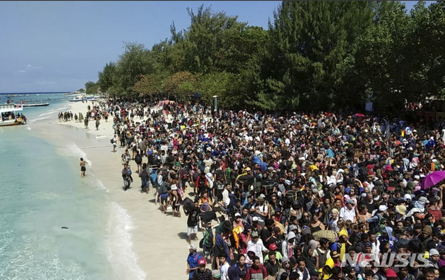 【질리 트라완간=AP/뉴시스】 규모 7.0의 강진으로 98명이 사망한 인도네시아 롬복 섬 바로 옆에 소재한 3개의 작은 섬 질리에서 6일 수천 명의 관광객들이 섬에서 빠져나가기 위해 여객선을 기다리고 있다. 질리 섬은 발리와 롬복 사이에 있다. 롬복 사망자는 전원 인도네시아 주민이며 2만 명이 집을 버리고 피난했다. 사망자 대부분은 붕괴된 건물의 파편에 맞았다. 2018. 8. 6.