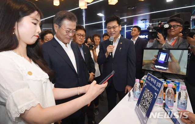 【서울=뉴시스】전신 기자 = 문재인 대통령이 7일 서울 중구 서울시 시민청 활짝라운지에서 열린 인터넷 전문은행 규제혁신 현장 방문 행사를 마친 후 페이콕 부스에서 핀테크 기술을 활용한 QR코드 결제 방식에 대해 설명 듣고 시연하고 있다. 2018.08.07. photo1006@newsis.com