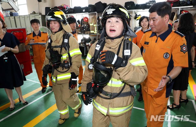 【화성=뉴시스】박진희 기자 = 문재인 대통령 부인 김정숙 여사가 8일 오후 경기도 화성시 화성소방서를 방문해 박가영 소방사의 설명을 들으며 특수 방화복을 착용하고 있다. 2018.08.08. pak7130@newsis.com