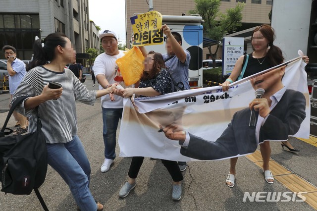 【서울=뉴시스】 조성봉 기자 = 성폭행 등 혐의로 기소됐던 안희정 전 지사가 1심에서 무죄를 선고받은 14일 서울 마포구 서부지법 앞에서 한 여성이 안 전 지사를 지지하는 사람들의 플래카드를 빼앗으려 하고있다. 2018.08.14. photo@newsis.com