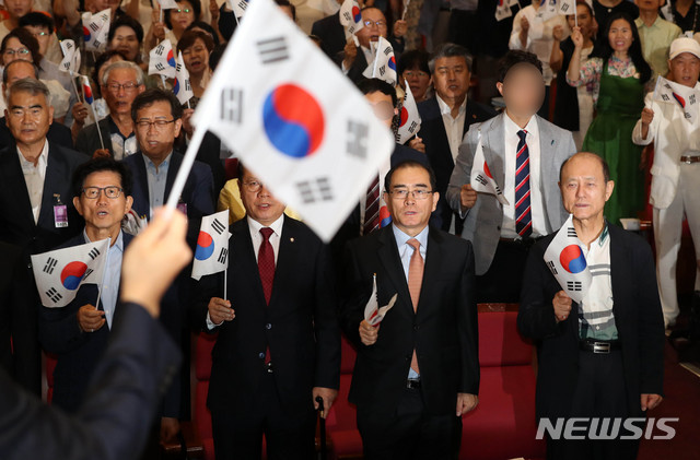 【서울=뉴시스】홍효식 기자 = 태영호 전 영국 주재 북한대사관 공사 등 참석자들이 15일 오전 서울 여의도 국회 의원회관에서 열린 대한민국 건국 70주년 기념식에 참석해 태극기를 들고 광복절 노래를 부르고 있다. 왼쪽부터 김문수 전 경기지사, 자유한국당 이종명 의원, 태영호 전 공사. 2018.08.15.&nbsp; yesphoto@newsis.com