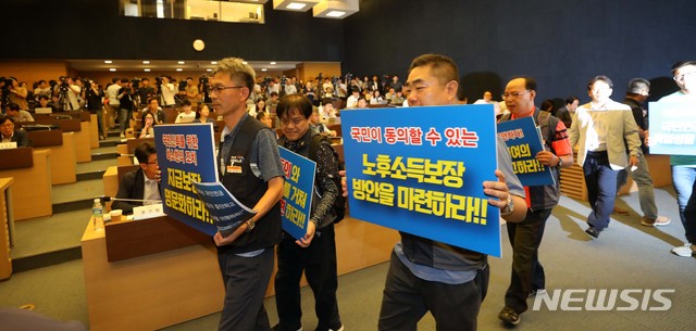 【서울=뉴시스】고범준 기자 = 17일 오후 서울 중구 세종대로 대한상공회의소 의원회의실에서 열린 2018년 재정계산 결과를 바탕으로 한 '국민연금 제도개선 방향에 관한 공청회'에서 공적연금강화 국민행동 소속 회원들이 '지급 보장 명문화' 등을 촉구하는 손 피켓을 들고 이동하고 있다. 2018.08.17. bjko@newsis.com