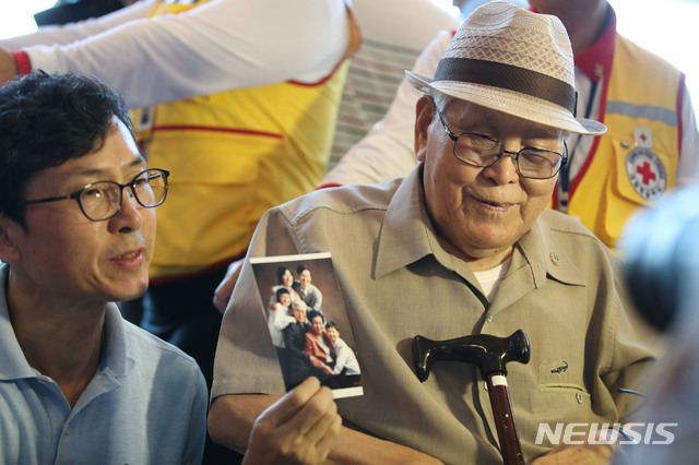 【속초=뉴시스】김진아 기자 = 21차 이산가족 상봉을 하루 앞둔 19일 오후 강원도 속초 한화리조트에서 남측 1차 상봉 대상자인 유관식(89) 할아버지와 가족들이 인터뷰 중 가족사진을 보여주고 있다. 유 할아버지는 4촌과 딸을 만날 예정이다. 2년10개월 만에 열리는 이번 이산가족 상봉 행사에는 이산가족 89명과 동반가족 108명 등 총 197명이 20일부터 22일까지 열리는 '1차 이산가족 상봉행사'에 참여할 예정이다. 2018.08.19. bluesoda@newsis.com