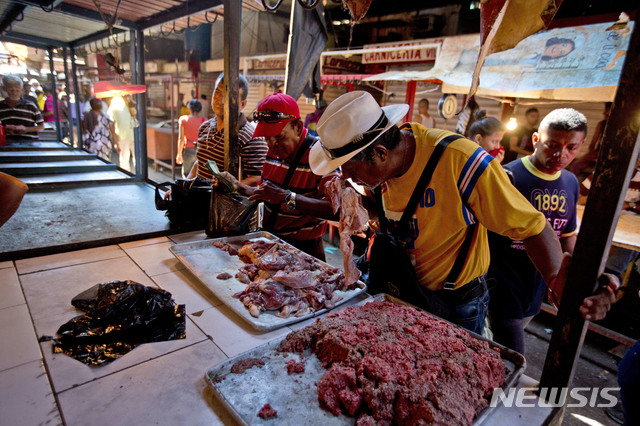【마라카이보(베네수엘라)=AP/뉴시스】최악의 경제 위기에 빠진 베네수엘라 제2의 도시 마라카이보에서 지난 19일 한 남성이 잦은 정전으로 상한 고기를 파는 한 정육점에서 부패 정도를 알아보기 위해 상한 고기의 냄새를 맡고 있다. 상한 고기를 먹고 탈이 나는 사람들도 있지만 빈곤층은 싼 가격 때문에 어쩔 수 없이 상한 고기를 산다. 2018.8.23
