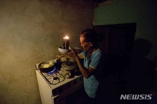 【마라카이보(베네수엘라)=AP/뉴시스】최악의 경제 위기에 빠진 베네수엘라 제2의 도시 마라카이보에서 지난 19일 한 주부가 정전으로 어두운 주방에서 촛불을 켠 채 저녁을 준비하고 있다. 마라카이보에선 잦은 정전으로 냉장고에 보관했던 고기가 상하면서 이로 인한 손실을 견디지 못한 정육점들이 헐값에 상한 고기를 판매하고 있는데 싼 가격 때문에 어쩔 수 없이 상한 고기를 사먹는 빈곤층이 많아 정육점 앞에 줄을 설 지경이다. 2018.8.23